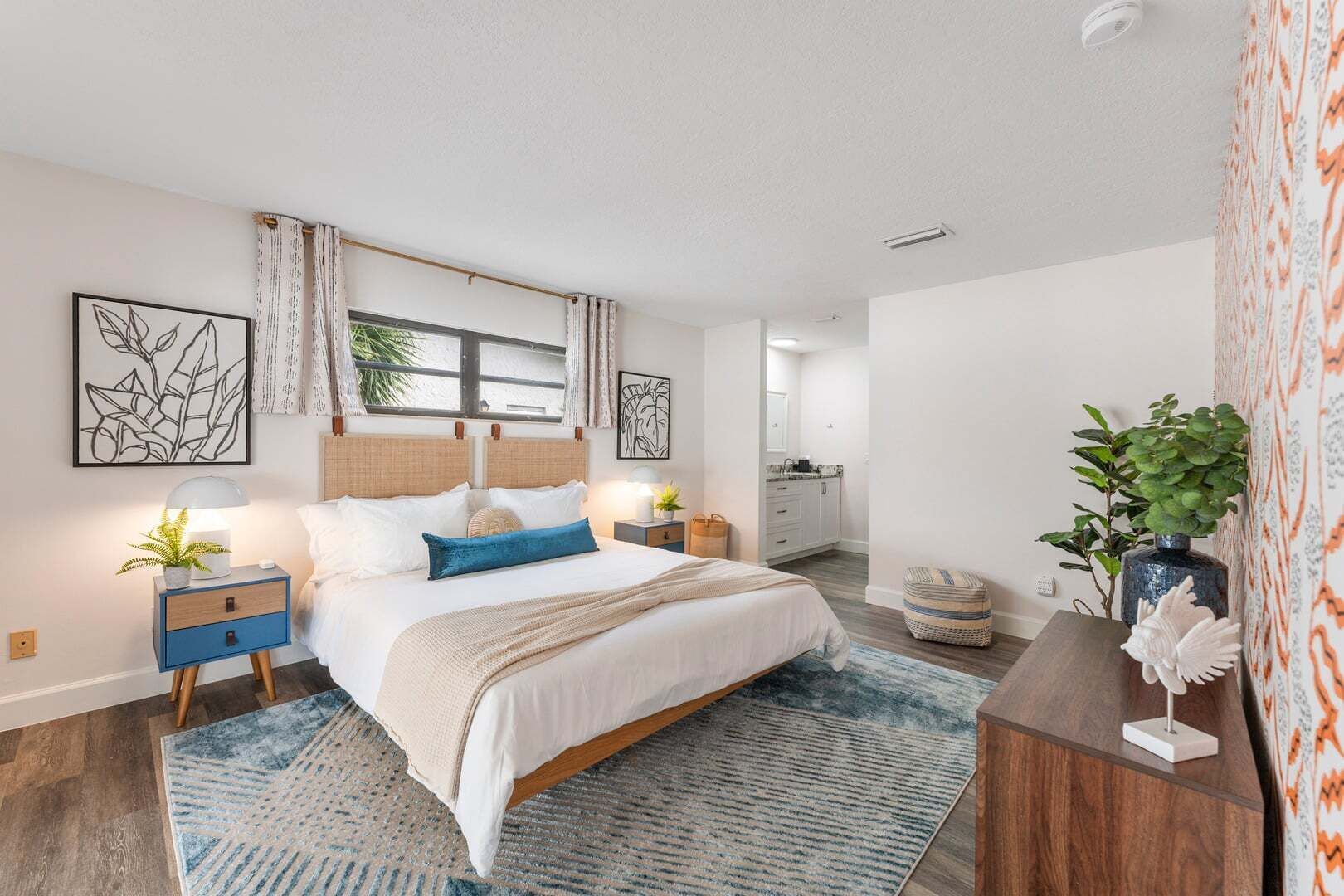 A bedroom with a bed, nightstands, a dresser, and a window with curtains.