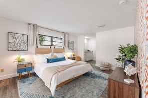 A bedroom with a bed, nightstands, a dresser, and a window with curtains.