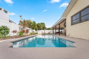 A swimming pool with a patio area, surrounded by plants and a white fence. - 311 Jack Dr (Cocoa Beach)