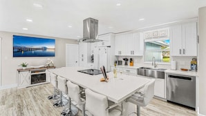 A modern kitchen with a central island, stainless steel appliances, and a large window. - 332 Formosa Drive (Cocoa Beach)