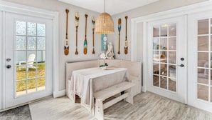 A room with a wooden bench, a table with a white tablecloth, and a wall with decorative paddles. - 332 Formosa Drive (Cocoa Beach)