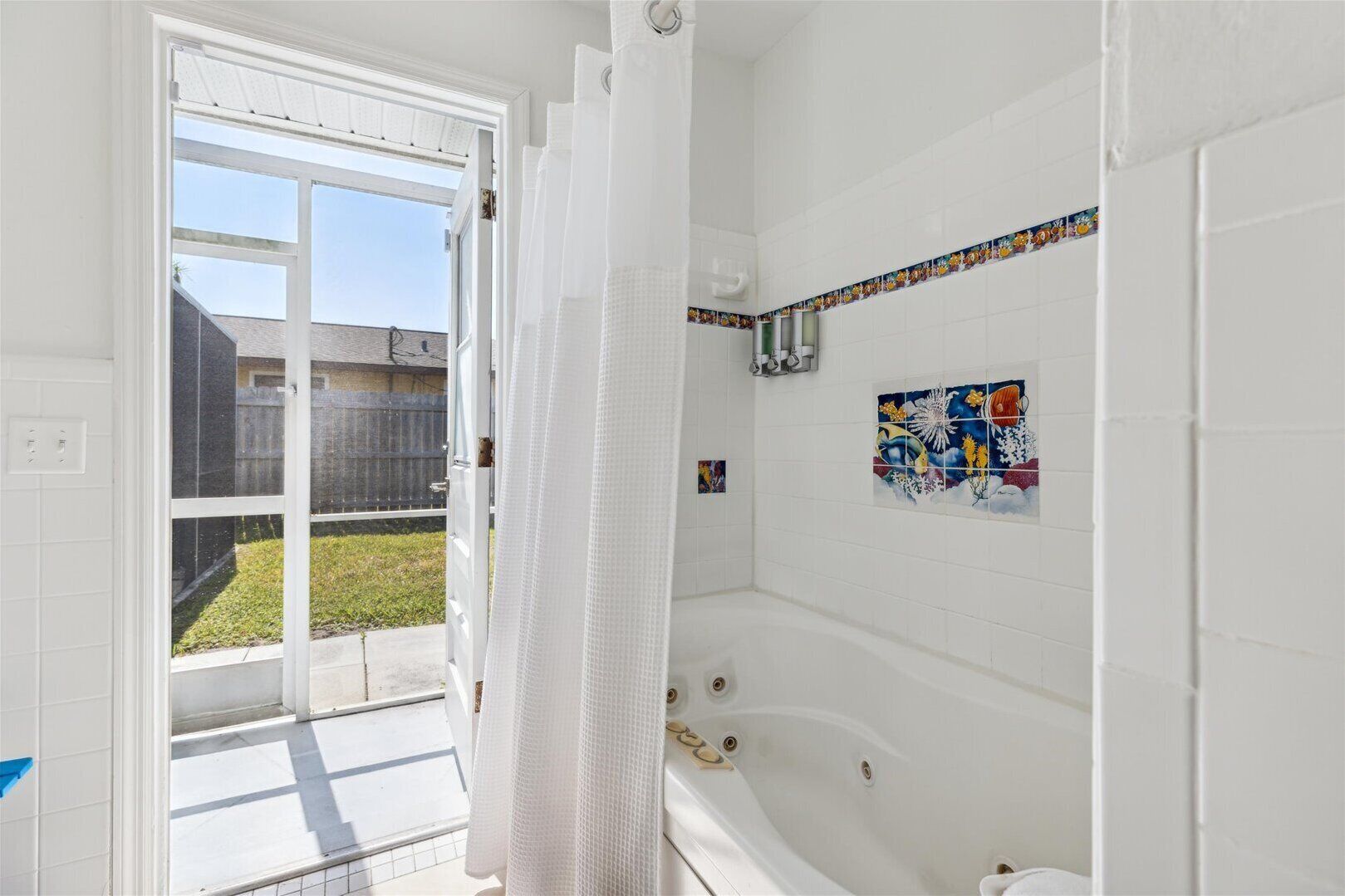 Ein Badezimmer mit einer Badewanne, einer Duschvorhang und einer gefliesten Wand mit floralem Muster.