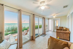 A spacious room with a large sliding glass door leading to a balcony with a view of the ocean.