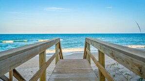 A wooden boardwalk leading to a beach with clear blue water and a sandy shore. - 3435 S Highway A1A (Melbourne Beach)