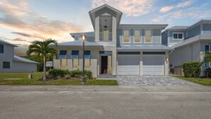 A two-story residential building with a garage, a covered front porch, and a landscaped front yard. - 132 Ocean Estates Dr (Fort Pierce)