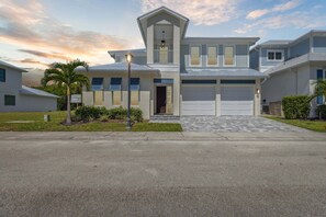 A two-story residential building with a garage, a covered front porch, and a landscaped front yard. - 132 Ocean Estates Dr (Fort Pierce)