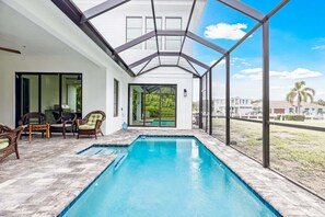 A covered swimming pool with a glass enclosure, wicker furniture, and a view of the outdoors. - 140 Ocean Estates Dr (Fort Pierce)
