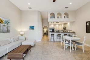 A modern interior with a sofa, dining table, kitchen, and artwork. - 110 Mediterranean Way (Indian Harbour Beach)