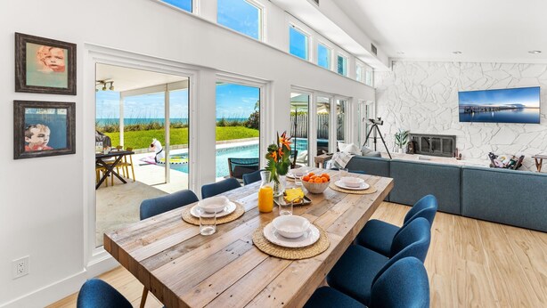 Un'ampia cucina con un'isola grande, un'area pranzo con sedie blu e vista su piscina e giardino.