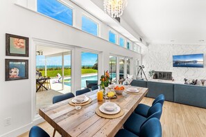A spacious kitchen with a large island, a dining area with blue chairs, and a view of a pool and garden. - 5435 Highway A1A (Melbourne Beach)