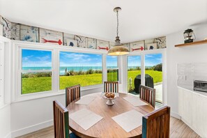 A dining area with a view of the ocean, a wooden table, and chairs. - 5435 Highway A1A (Melbourne Beach)