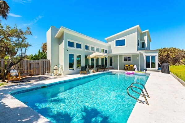 A modern two-story house with a swimming pool, outdoor seating, and a covered patio. - 5435 Highway A1A (Melbourne Beach)