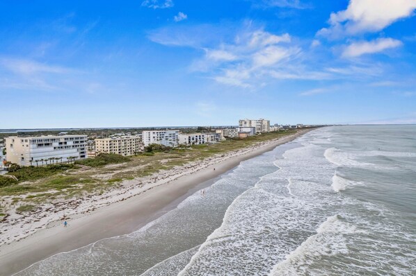 A coastal hotel with multiple buildings along the beachfront, featuring a sandy beach and ocean views.