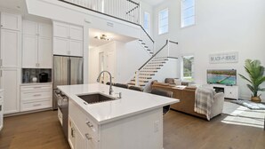 A modern kitchen with white cabinetry, a central island, and a stainless steel refrigerator.