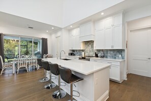 Enjoy cooking and dining in this spacious kitchen with a large island, bar stools, and a dining area with a glass-top table.