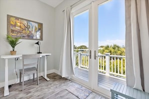 A balcony with a view of greenery and a painting on the wall.