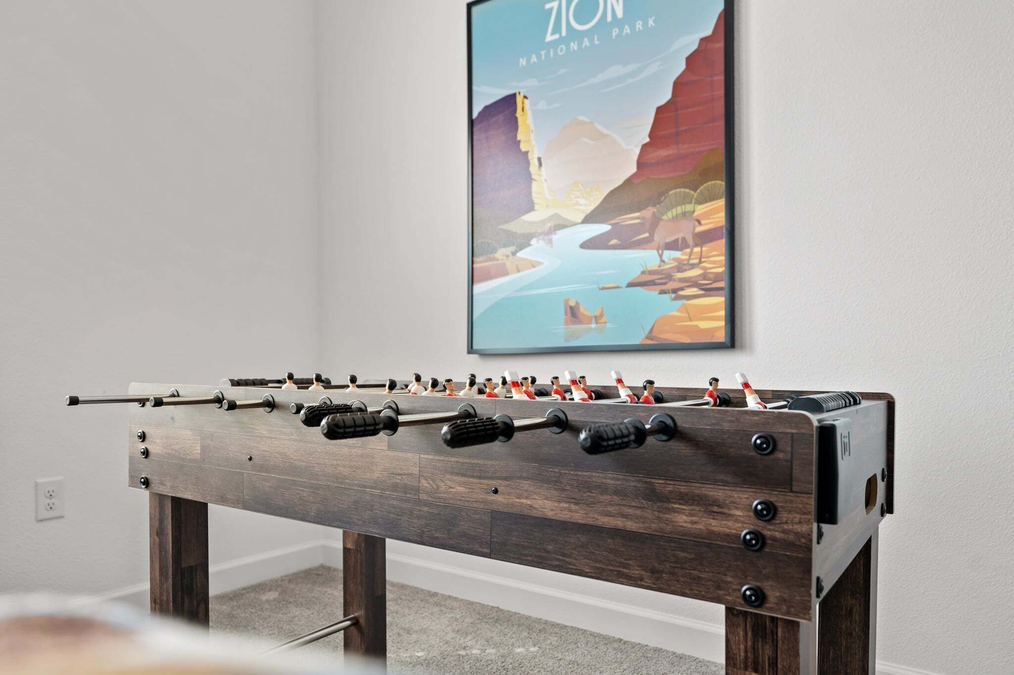 Een tafelvoetbaltafel met een poster van Zion National Park op de achtergrond.