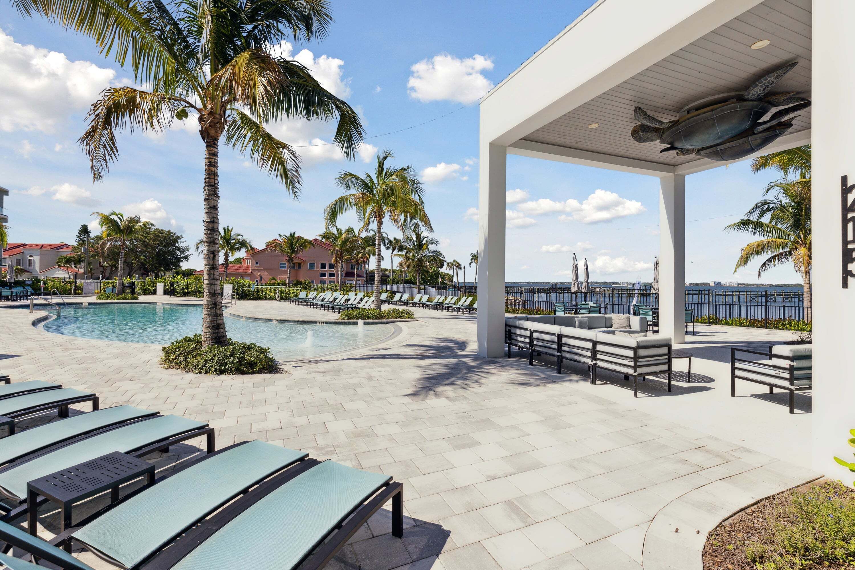 A poolside area with lounge chairs, a covered seating area, and a view of the ocean.