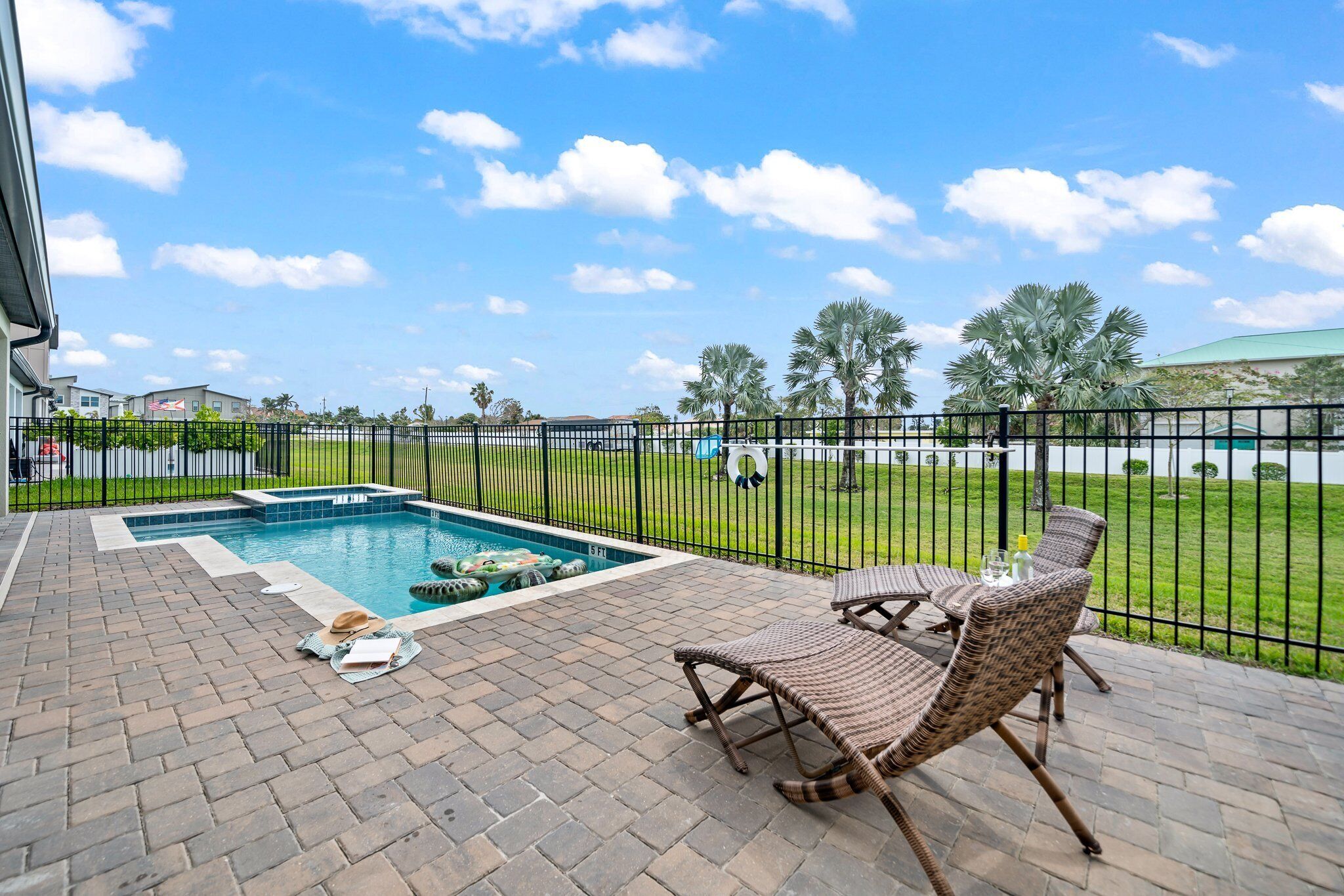 A pool area with lounge chairs, a brick patio, and a view of the surrounding landscape.