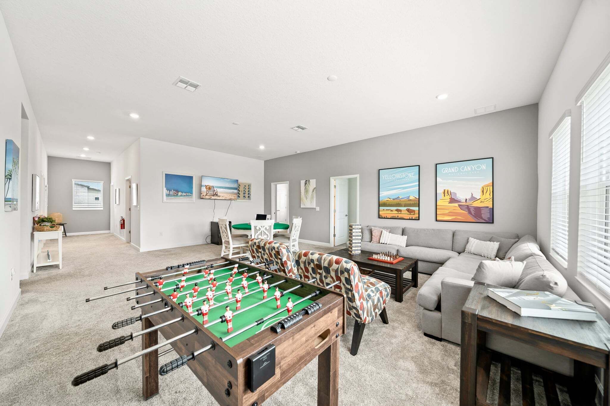 A spacious living room with a foosball table, a sofa, a coffee table, and artwork on the walls.