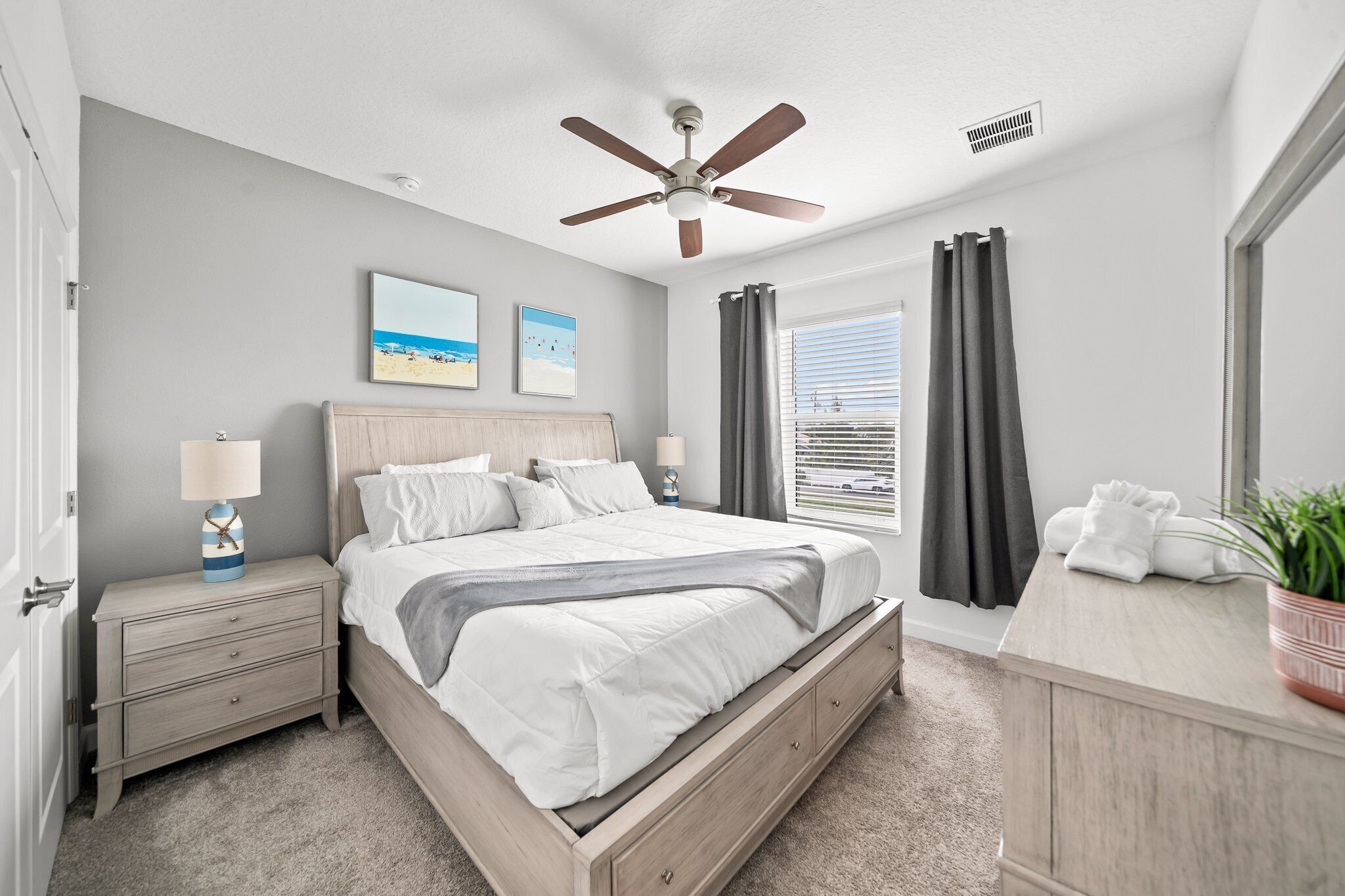 A bedroom with a bed, nightstand, and a ceiling fan.