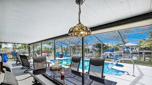 Ett takförsett utomhusområde med en pool, sittplatser och en hängande lampa.