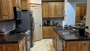 Una cocina con armarios de madera, un refrigerador de acero inoxidable, una estufa y un lavamanos.
