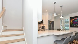 Een moderne keuken met een centraal eiland, roestvrijstalen apparatuur en hanglampen.