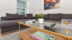 Een moderne woonkamer met een grijze bank, een glazen salontafel en een spel.