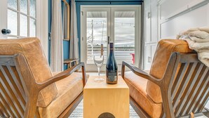 Een kamer met twee leren stoelen, een houten tafel en een fles wijn.