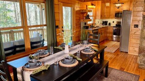 Une cuisine chaleureuse, aménagée dans le style d’un chalet, avec des meubles en bois, une table à manger pour quatre personnes et un mur en pierre.