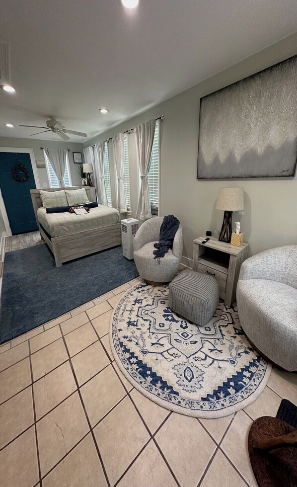 A modern bedroom with a bed, a round rug, a chair, and a nightstand.