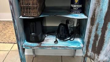 A shelf with a basket, a container of Morton salt, and a black bag.
