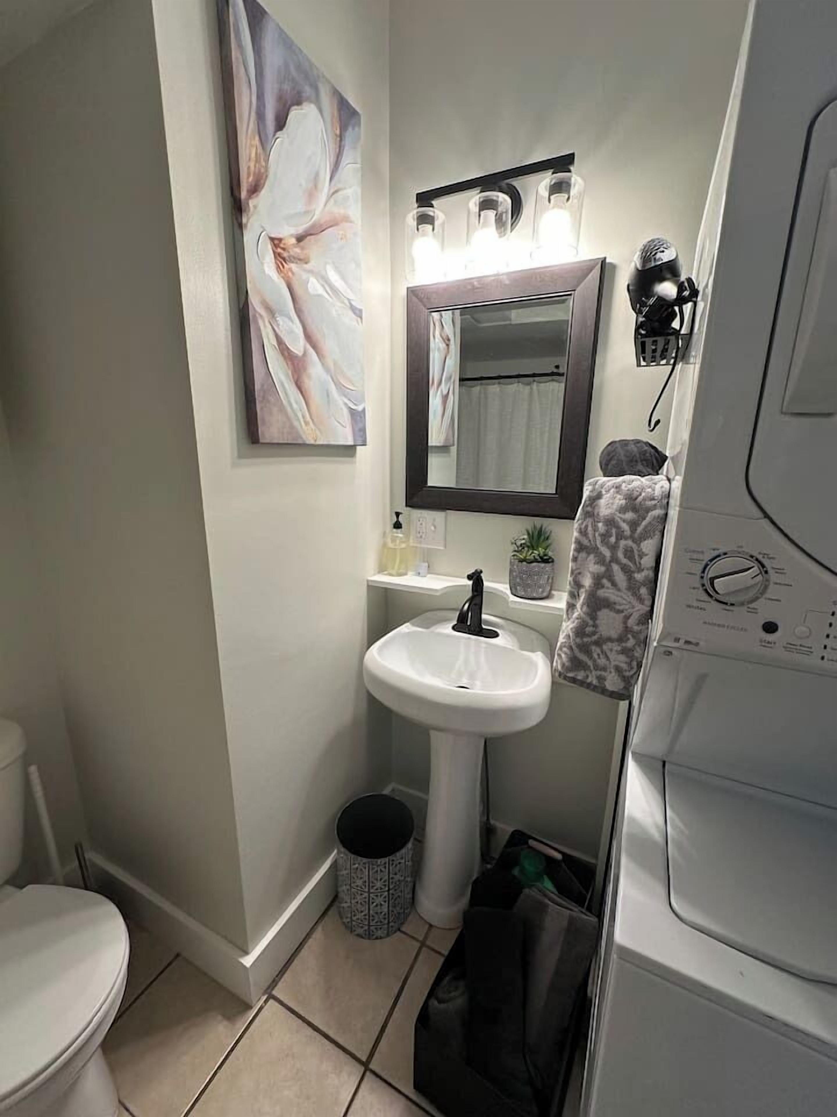 A compact bathroom with a white sink, a mirror, and a toilet.