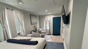 Une chambre d’hôtel moderne équipée d’un lit, d’un bureau, d’une chaise, d’une télévision et d’une porte.