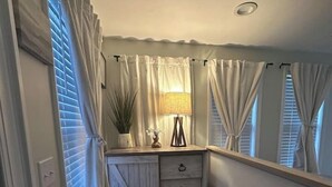 Un couloir étroit avec une commode en bois, un miroir et une lampe.