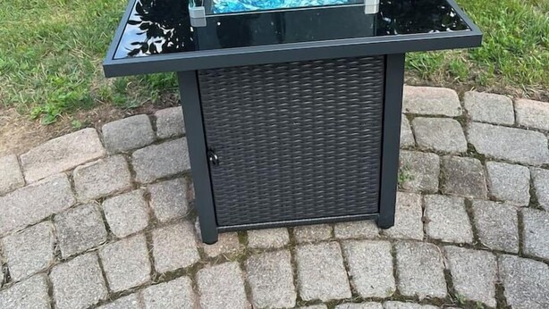 Une fontaine extérieure de forme carrée, dotée d’une surface réfléchissante et entourée d’une bordure en pierre.