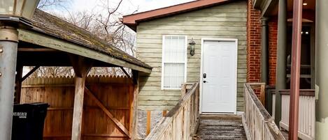 A wooden pathway leading to a white door, a wooden fence, and a metal lamp post.