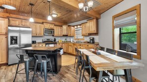 A modern kitchen with wooden cabinets, stainless steel appliances, and a central island with bar stools.