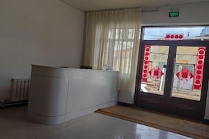 A reception area with a reception desk, a window with curtains, and a door with a glass panel.