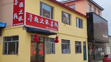 A two-story building with a yellow facade, a red awning, and a signboard with Chinese characters.