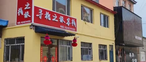 A two-story building with a yellow facade, a red awning, and a signboard with Chinese characters.