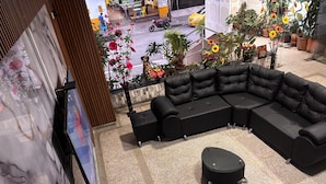A modern interior with a sectional sofa, a small round table, and a decorative wall with a floral painting. - Hotel Los Arcangeles (San Jose de Cucuta)