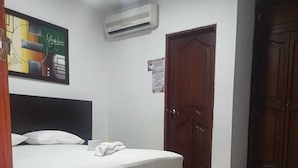 A bedroom with a bed, an air conditioner, a door, and a wall with a poster. - Hotel Los Arcangeles (San Jose de Cucuta)