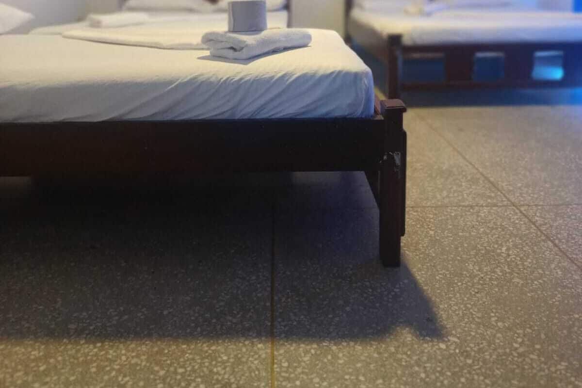 Ein Hotelzimmer mit zwei Einzelbetten, beide mit Holz-Kopfteilen und weißen Bettwäsche. Über den Betten ist ein gerahmtes Bild an der Wand zu sehen.
