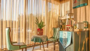 A room with a large window, a green chair, a small table with a plant, and a cabinet with various items. - Jinjiang Inn (LinyiWanxianghui Railway Station Hotel) (Linyi)