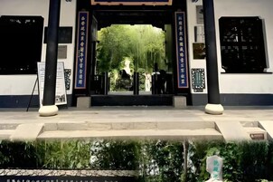 A traditional building entrance with a large gate, two pillars, and a signboard.