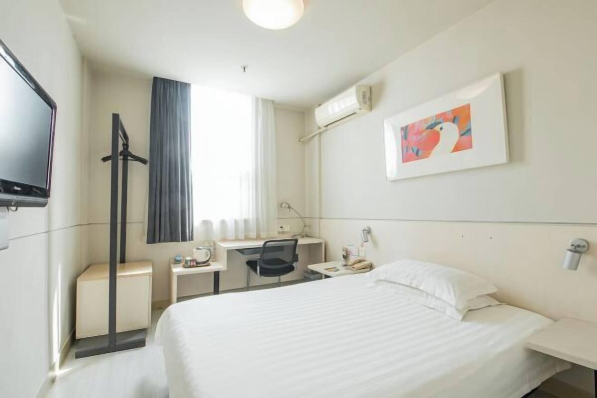 Habitación de hotel con cama, escritorio, silla y televisor.