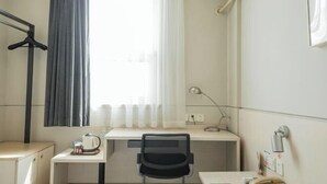 A hotel room with a desk, chair, and a hanging coat rack. - Jinjiang Inn (LinyiWanxianghui Railway Station Hotel) (Linyi)