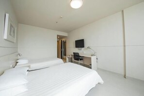A hotel room with two beds, a desk, a chair, a flat-screen TV, and a framed picture on the wall. - Jinjiang Inn (LinyiWanxianghui Railway Station Hotel) (Linyi)